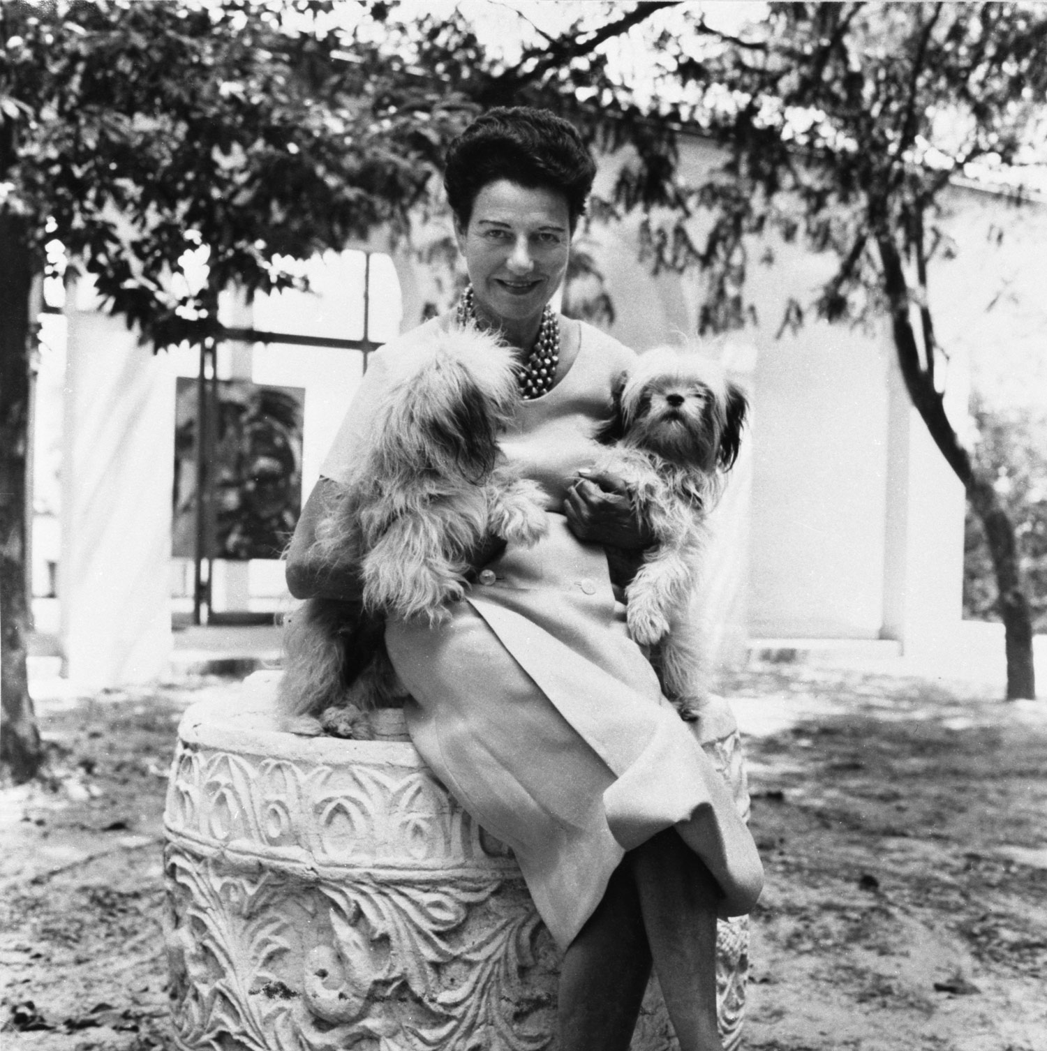 Peggy Guggenheim nel giardino di Palazzo Venier dei Leoni, Venezia, anni Cinquanta. Alle sue spalle Karel Appel, Il coccodrillo piangente cerca di afferrare il sole (The Crying Crocodile Tries to Catch the Sun), 1956. Photo Roloff Beny / courtesy of Archives and National Archives of Canada.
