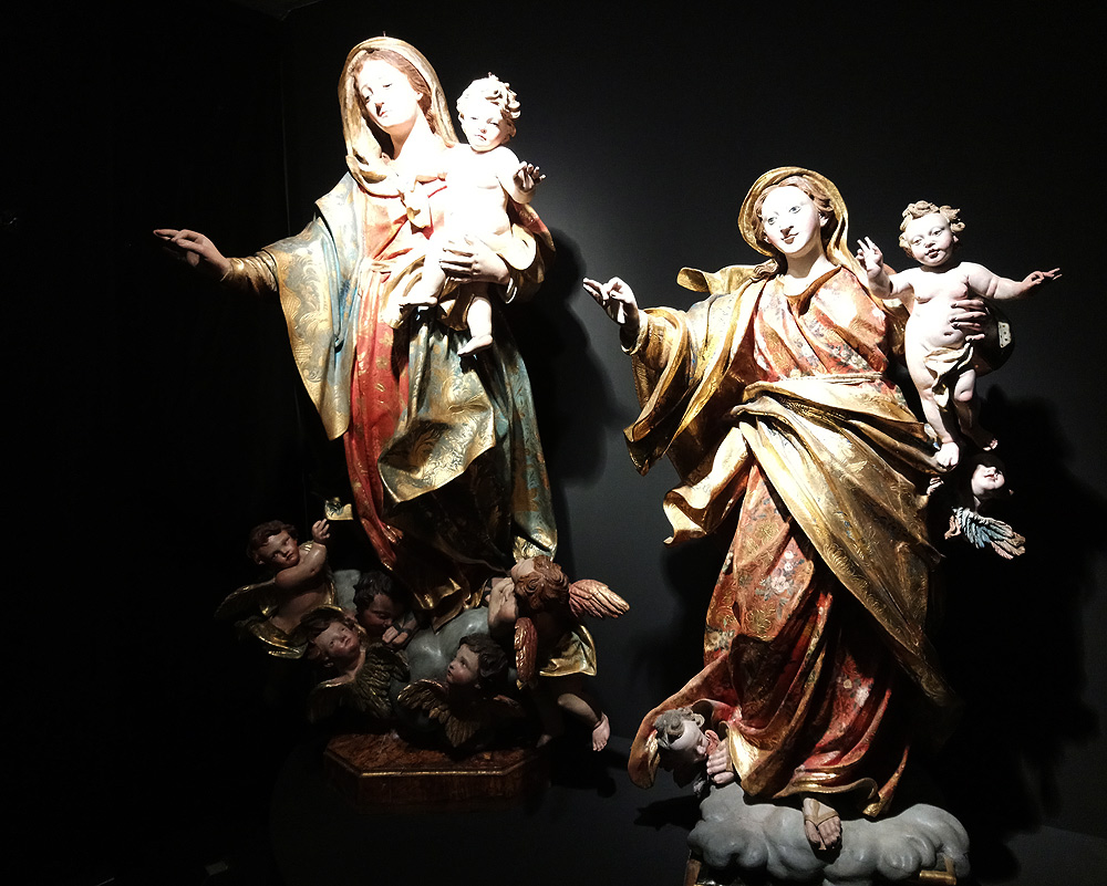 A sinistra, Agostino Storace, Madonna del Rosario (dopo il 1743; legno scolpito e dipinto, occhi in pasta vitrea, 140 x 70 x 60 cm; Garbagna, San Giovanni Battista). A destra, Giovanni Maragliano, Madonna del Rosario (prima del 1750; legno scolpito e dipinto, 138 x 77 x 60 cm; Neirone, San Maurizio)
