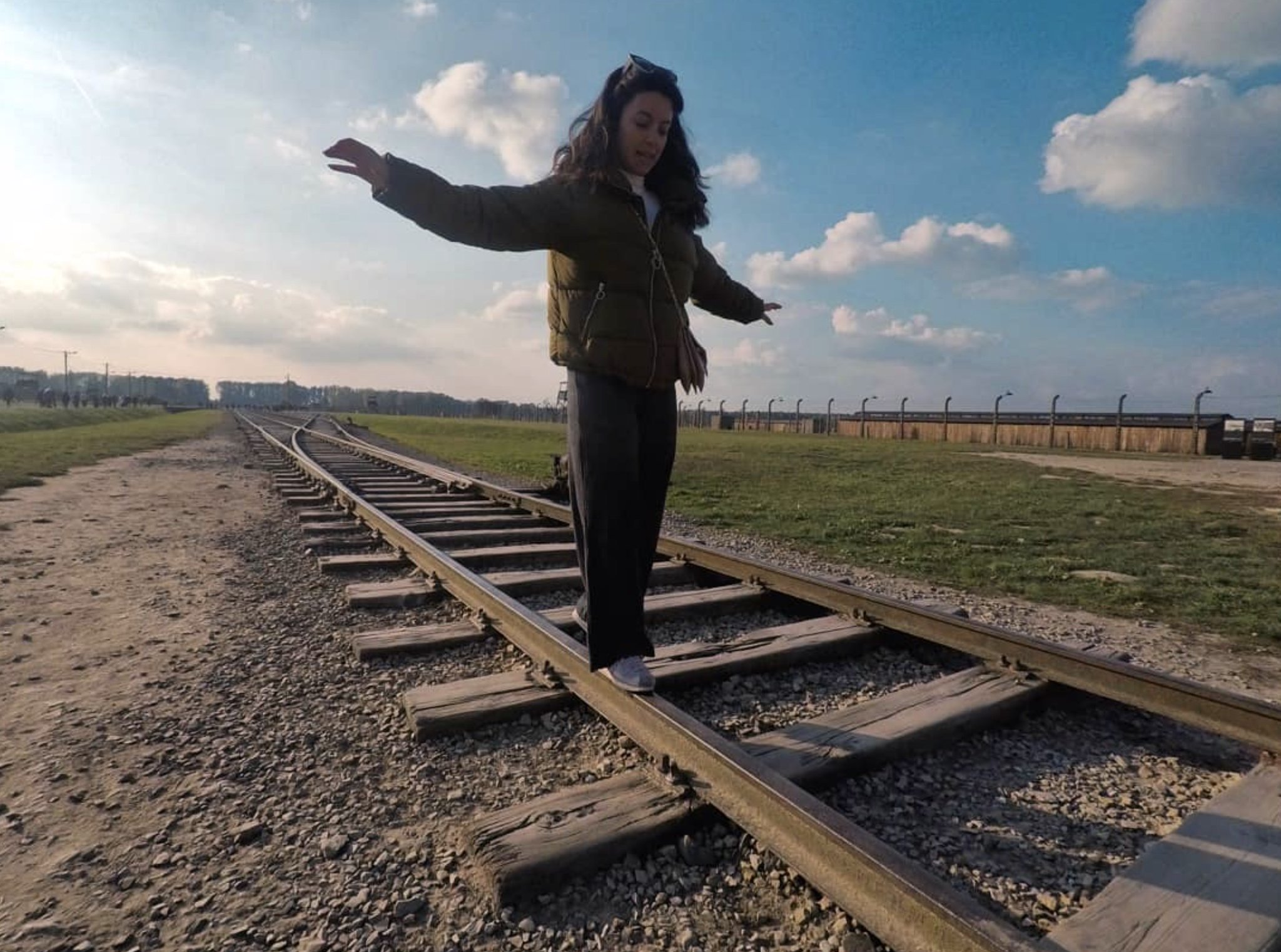 Una visitatrice di Auschwitz in equilibrio sui binari della ferrovia che conduceva al campo di sterminio