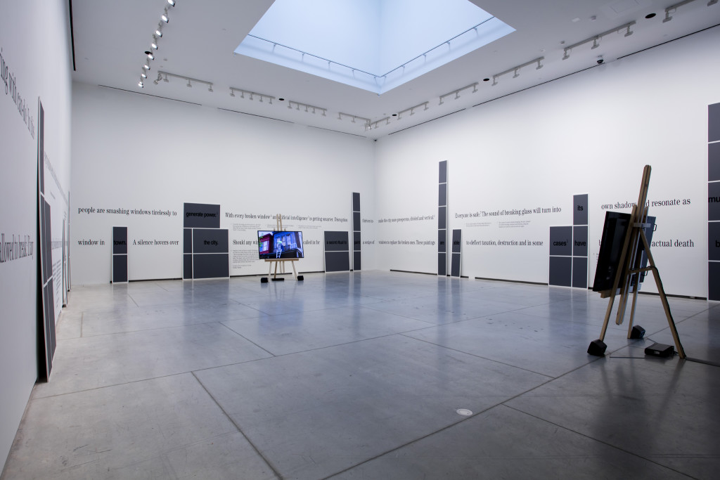 Hito Steyerl, The city of broken windows (2018; video file HD due canali, colore suono, adesivi di vinile, cavalletti, pittura a olio, dimensioni variabili)
