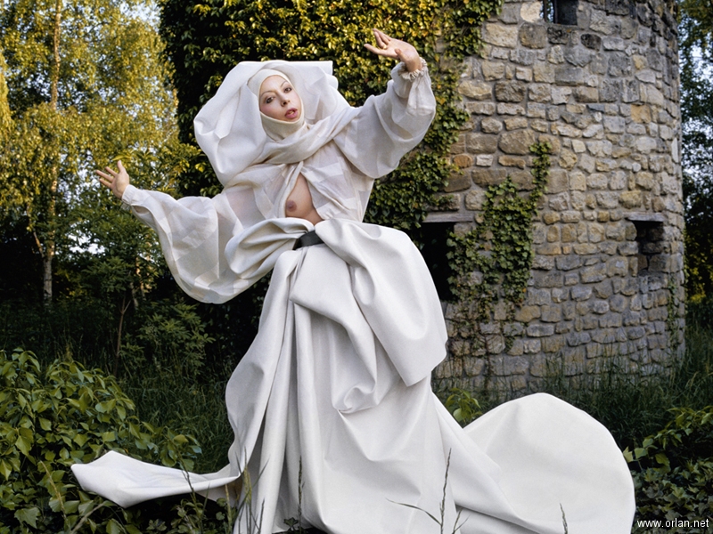ORLAN, Étude Documentaire : Le Drapé-Le Baroque, Sainte ORLAN se joue aux images bucoliques de mariage (1986; fotografia a colori, 110 x 165 cm) ORLAN, Étude Documentaire : Le Drapé-Le Baroque, Sainte ORLAN se joue aux images bucoliques de mariage (1986; fotografia a colori, 110 x 165 cm)